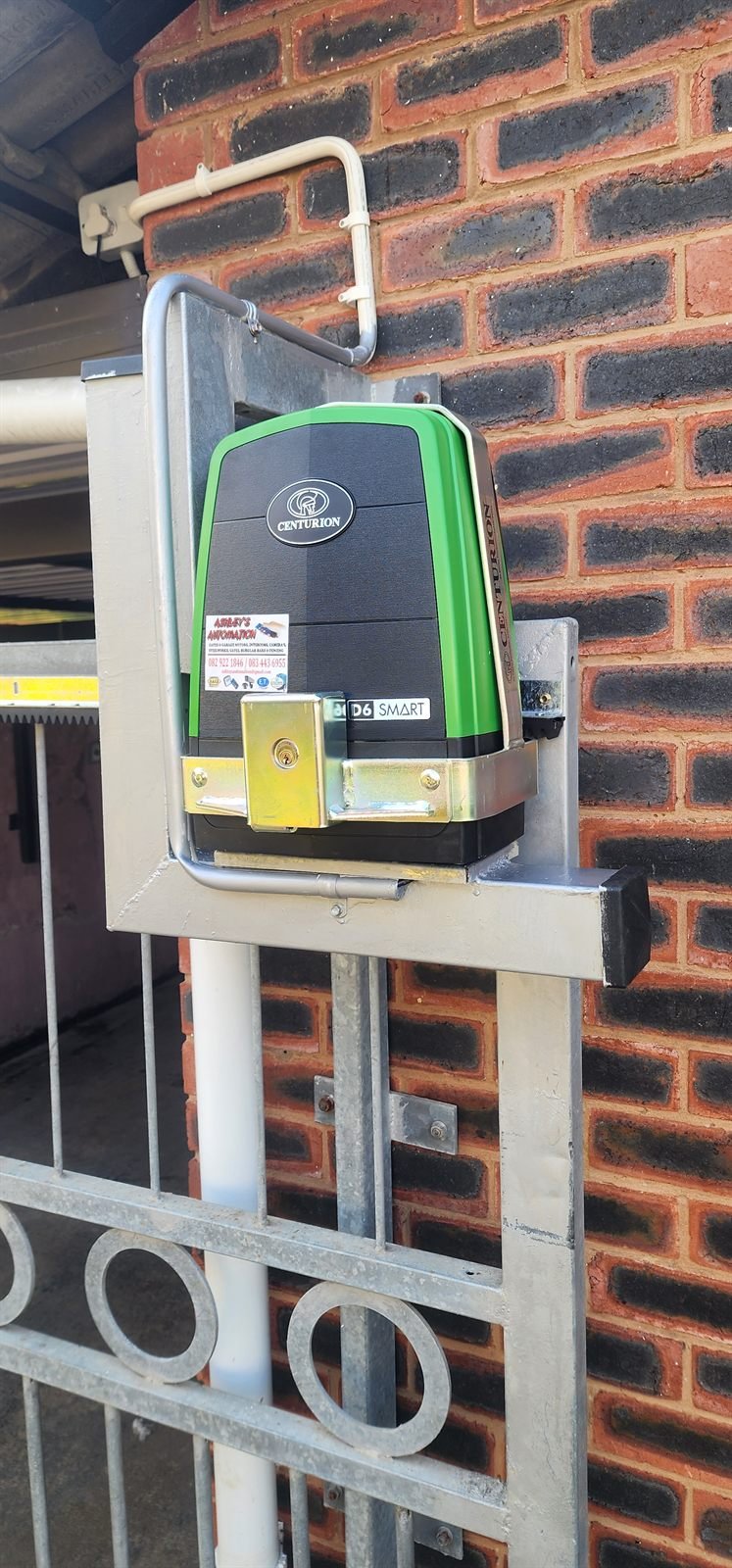 Gate motor mounted in a steel anti-theft bracket on a brick pillar
